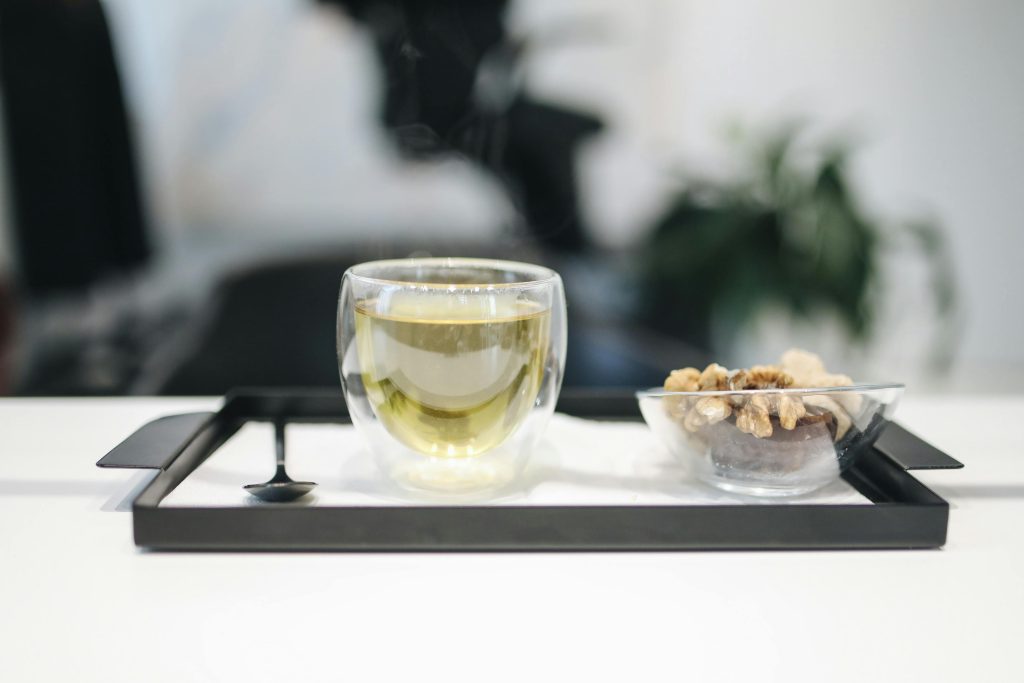 A modern tea and walnut snack setup on a tray with a cozy indoor background.