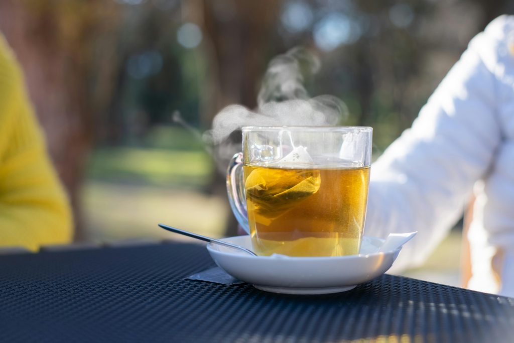 A clear glass teacup steaming on an outdoor table in Portugal, perfect for relaxation.
